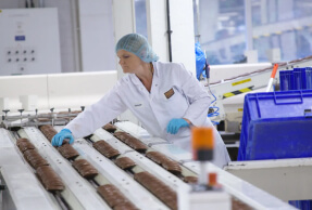 A woman wearing a hair net working in a biscuit factory